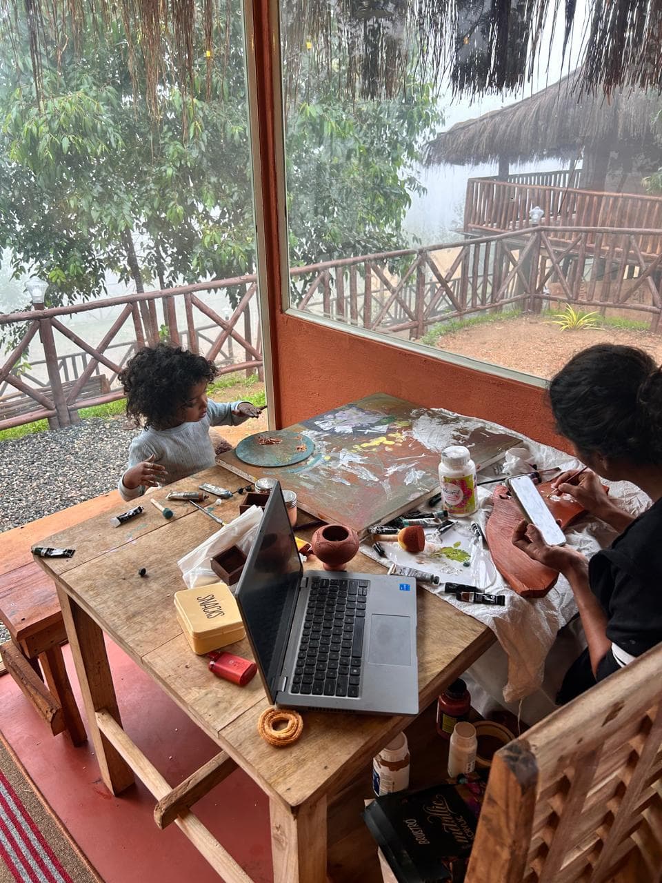 Guests painting at a wooden table beside a window overlooking the garden