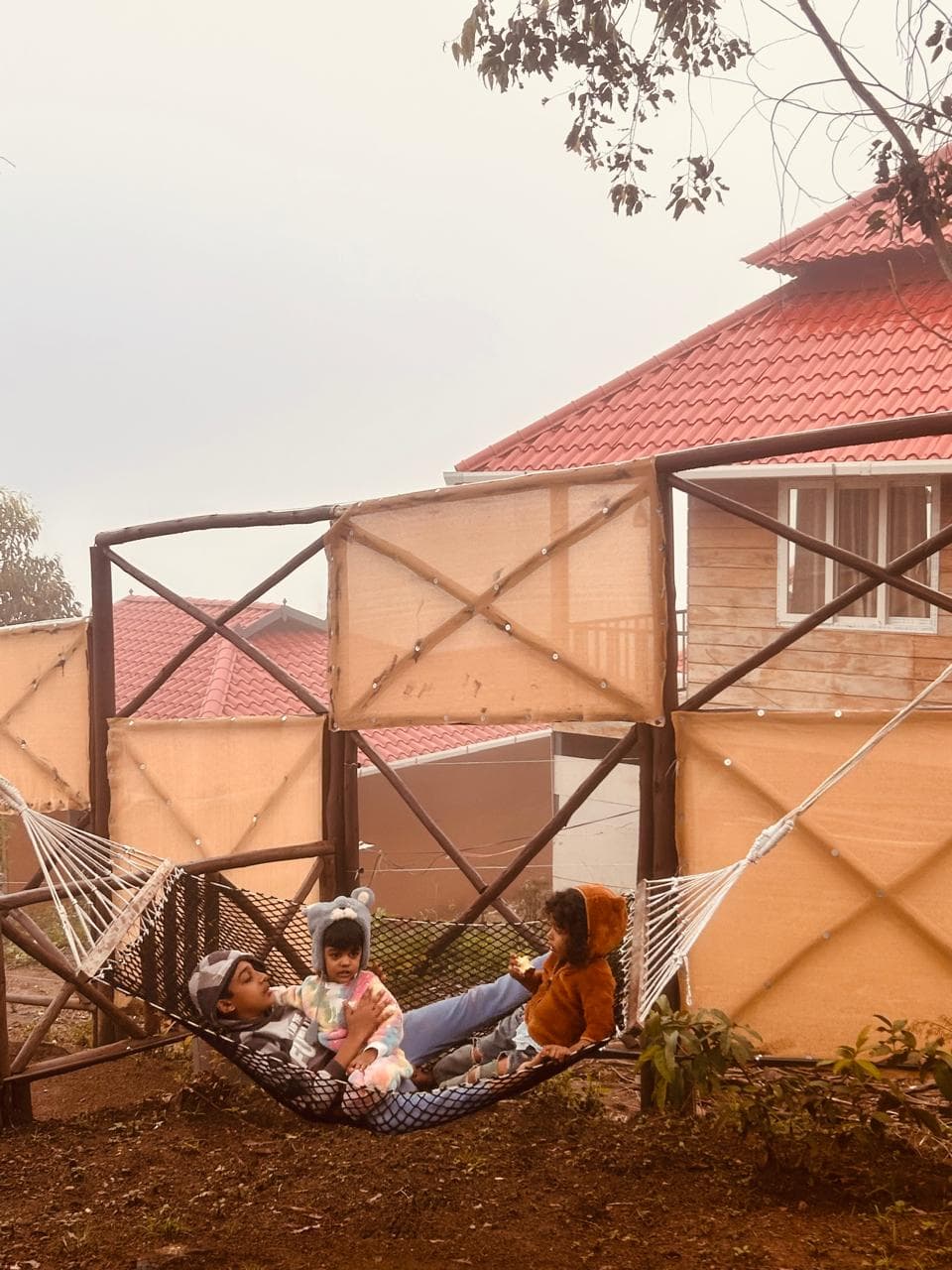 Children swinging in a hammock outside a cottage