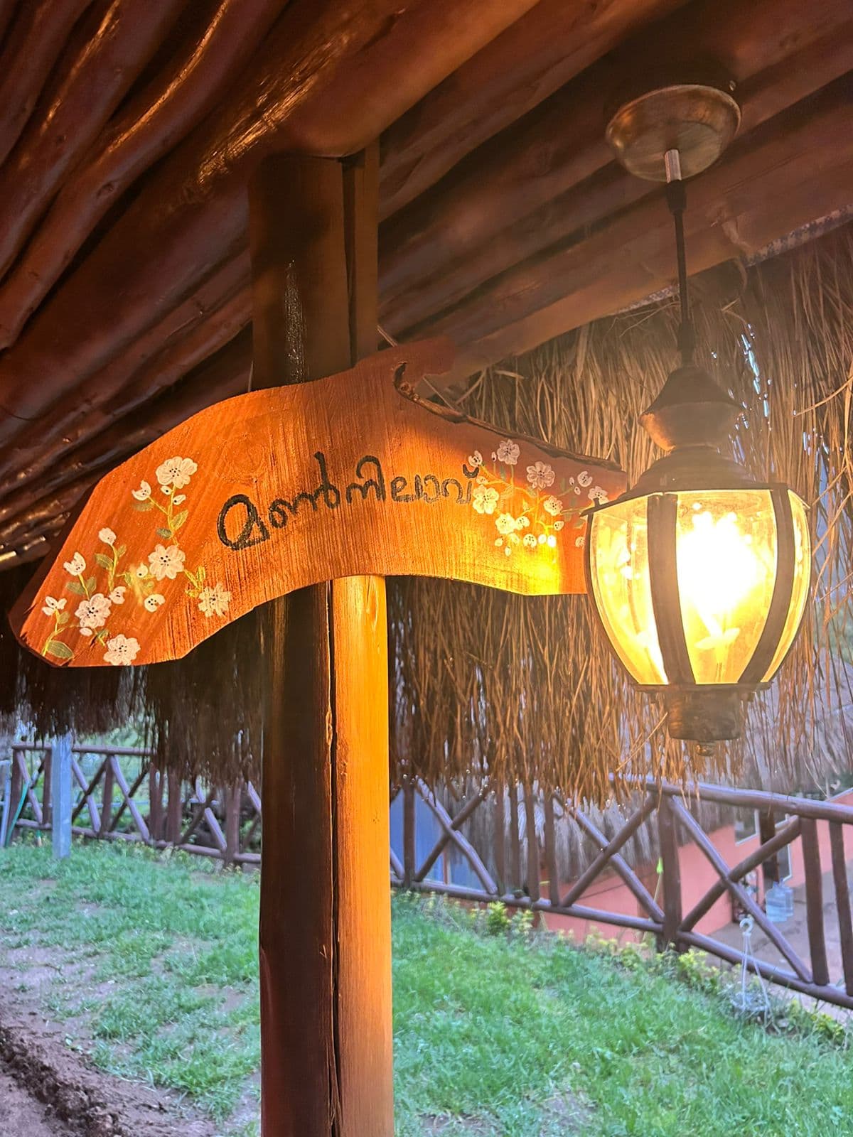 The hand-painted Mannilave sign lit by a lantern